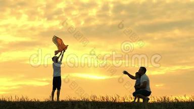 快乐的父亲，家人和孩子，在夏天的日落时，缓慢地跑进风筝的天空。 家庭户外